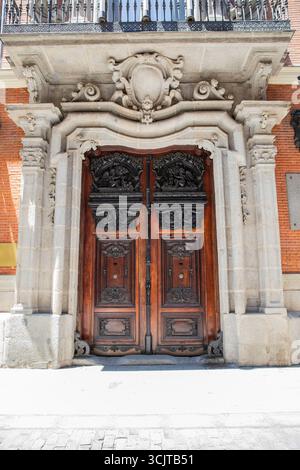 Herrlicher Eingang mit massiver Holztür, dekoriert mit Skulpturen und Schnitzereien. Antik geschnitzte Holztüren und Steinbogen. Madrid Spanien 08.06.2 Stockfoto