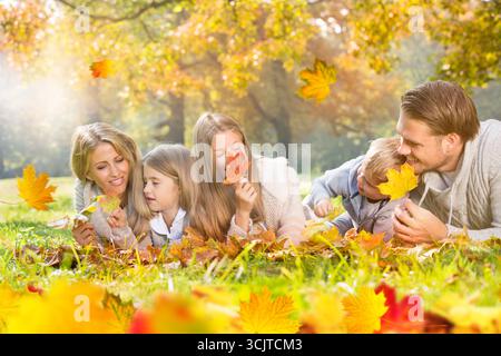 Familie mit drei Kindern, die im Herbst auf einer Wiese liegen Stockfoto