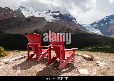 Zwei ikonische rote Parks Canada-Stühle bilden einen auffälligen Vordergrund für einen spektakulären Blick auf das Columbia-Eisfeld vom Wilcox Pass Trail in Alberta. Stockfoto