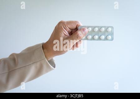 Mann, der einen Tablettenstreifen hält. Isoliert auf weißem Hintergrund, Nahansicht. Stockfoto