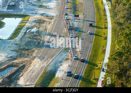 Aus der Vogelperspektive auf die stark befahrene amerikanische Autobahn im Bau. Entwicklung der Verkehrsinfrastruktur. Staatliches Transportkonzept. Stockfoto