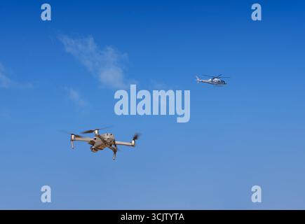Drohne im Flug am Himmel in die Nähe eines vorbeifahrenden kommerziellen Hubschraubers Stockfoto