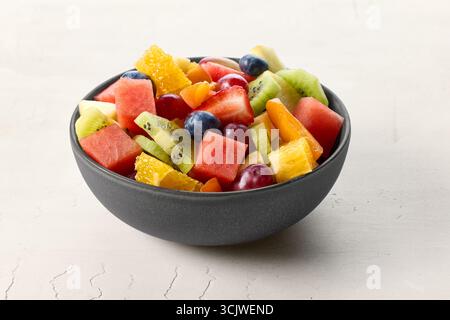 Frischer Obstsalat in schwarzer Schüssel für gesunde Ernährung Stockfoto