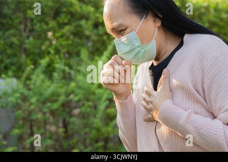 Ungesunde Krankheit, Seitenansicht Asiatische Frau trägt Maske Husten, haben Halsschmerzen, leiden Symptom Husten Gefühl. Schlechte und gesundheitliche Versorgung der Luftverschmutzung Stockfoto