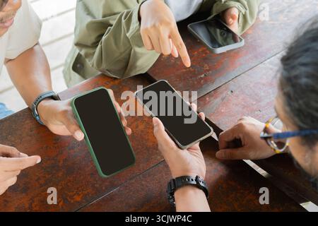 Draufsicht Gruppe von Personen, die ein Smartphone im Freien verwenden. Trendiges Technologiekonzept, bei dem Nutzer die App auf dem Smartphone nutzen Stockfoto