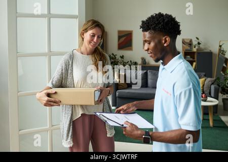 Frau erhält Paket von Black man Courier Stockfoto
