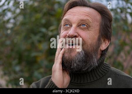 Porträt eines denkenden, träumenden oder Problemlösungsmannes. Ältere bärtige kaukasische Männer in der Natur. Gesicht bärtiger kaukasischer männlicher Tagtraum vom dezember Stockfoto