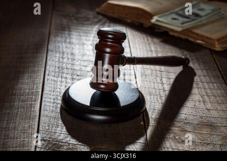Hölzerner Richter Hammer, Soundboard, altes Buch mit Dollars auf dem Hintergrund eines Holztisches, Nahaufnahme Stockfoto