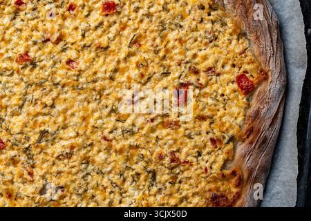 Hausgemachte frisch gekochte Pizza oder Kuchen mit Quark, Tomaten, Käse und Kräutern auf einem Blechblech nach dem Backen im Ofen, Nahaufnahme, Top V Stockfoto