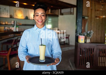 Junge schwarze Frau, die in einem stilvollen Café arbeitet, Vielfalt, Stolz auf eine moderne berufliche Umgebung Stockfoto