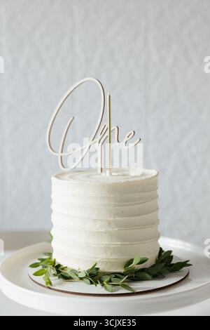 Eine bezaubernde Geburtstagskuche sitzt elegant auf einem weißen Teller mit zartem Frosting und festlichem Deckel. Stockfoto