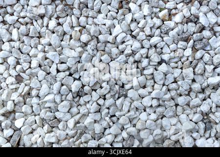 Hintergrund von kleinen weißen und grauen Steinen, die ein Muster bilden. Textur von Steinen. Naturkonzept Stockfoto