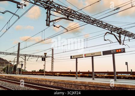 Garraf, Katalonien, Spanien. Abendlicher Blick auf die Bahngleise und den leeren Bahnsteig am Bahnhof Garraf mit flauschigen Wolken am Himmel Stockfoto