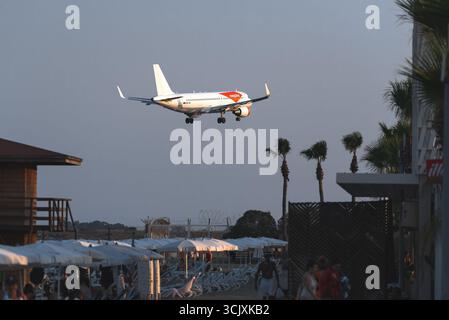 Larnaca, Zypern - 26. Juli 2025: Airbus A320-214 Passagierflugzeug der easyJet Airline landet über einem Strand von Mackenzie voller Touristen mit Sonnenschirm Stockfoto
