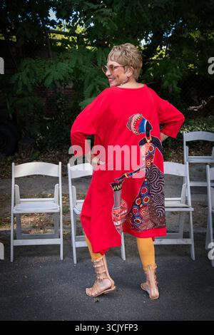Eine Frau mittleren Alters, die ein rotes Kleid mit afrikanischem Muster trägt. Auf der Wakanda 2025 in Mount Vernon, New York. Stockfoto