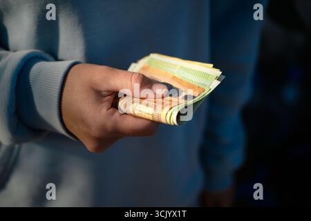 Nahaufnahme einer Person, die einen Stapel Euro-Banknoten in der Hand hält. Konzept der Einsparungen, Zahlung oder Transaktion. Stockfoto