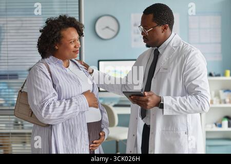 Schwarze Ärztin berät schwangere Schwarze Frau mittleren Alters in der Klinik Stockfoto