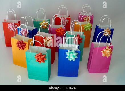 Bunte Einkaufstaschen aus Papier mit Schleife auf weißem Hintergrund. Stockfoto