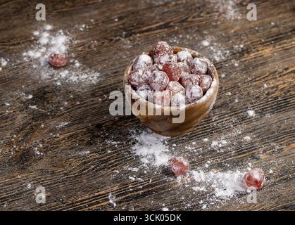 Getrockneter Kumquat und weißer Puderzucker in einer Holzschüssel werden trockene orange Kumquat-Früchte in eine Holzschüssel gegeben und mit weißer Rüben bestreut Stockfoto