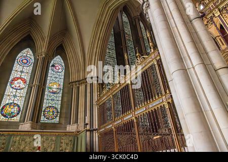 Das Innere der York Minster Cathedral mit farbenfrohen Buntglasfenstern, Spitzbögen und einem kunstvollen gotischen Chorschirm in York, England. Stockfoto