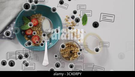 Die türkisfarbene Schüssel hält Müslijoghurt mit Beeren Minze auf weißer Tischplatte, mit Löffel Stockfoto