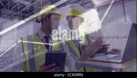 Kooperierende Ingenieure, die Schutzhelme und Westen zwischen Stahlträgern tragen, vor Ort mit Tablet und Laptop Stockfoto