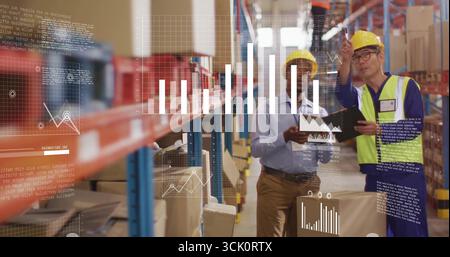 Zwei Männer mit Schutzhelmen, die Datenüberlagerungen im Lagergang überprüfen, mit Tablettenablage Stockfoto