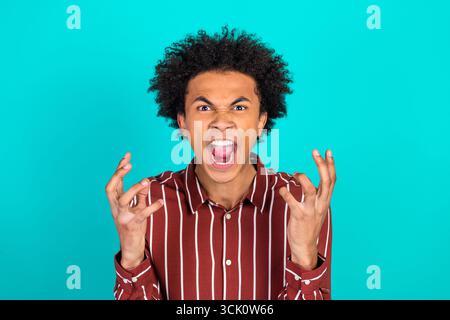Junger Mann, der intensive Emotionen in einer Studioumgebung mit modernem Modestil auf einem lebendigen Hintergrund ausdrückt Stockfoto