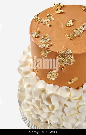 Köstlicher zweistufiger Kuchen, dekoriert mit Blattgold und weißer Creme Stockfoto