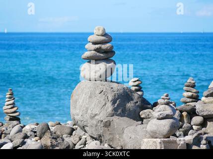 Stone Cairns nahe am Rocky Beach mit dem blauen Meer im Hintergrund. Stockfoto