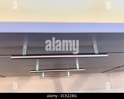 Nahaufnahme eines grauen Schranks mit Chromgriff in hellem Raum Stockfoto