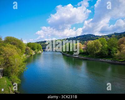 Ein malerischer Blick auf den Fluss Po, der durch Turin fließt, an einem hellen, sonnigen Tag. Das ruhige, blaue Wasser des Flusses wird von üppig grünen Blättern begrenzt Stockfoto