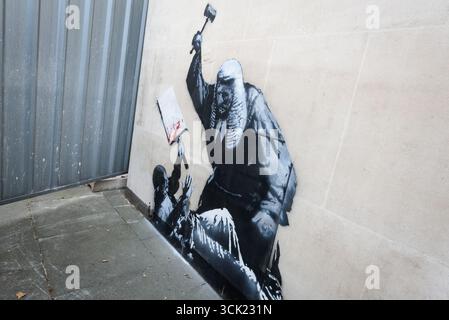 London, Großbritannien. 9. September 2025. Ein neues Werk des weltberühmten, anonymen Straßenkünstlers BANKSY erschien gestern vor den königlichen Justizgerichten, in dem ein Richter seinen Hammer auf einen niedergeschlagenen Demonstranten mit einem Plakat bringt. Es folgte auf die Verhaftung von 857 friedlichen Demonstranten auf dem Parlamentsplatz, die Plakate zur Unterstützung der Palästinensischen Aktion hielten. Verborgen von einem Metallschutzschirm war das Kunstwerk heute durch eine kleine Lücke sichtbar, und die Leute standen in der Warteschlange, um einen Blick zu erhalten. Derzeit ist unklar, was mit dem Graffiti geschehen wird. Quelle: Ron Fassbender/Alamy Live News Stockfoto