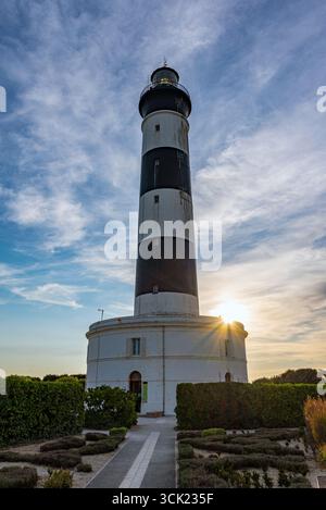 Der schwarz-weiße Leuchtturm von Chassiron bei Sonnenuntergang an der Nordspitze der Insel Oléron. Stockfoto