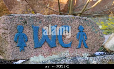 Wegweiser zur Toilette auf einem Stein gemalt. Stockfoto
