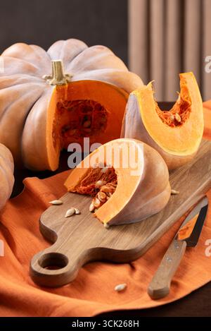 Frischer Musquee de Provence Kürbis mit geschnittenen Keilen und Samen auf Einem hölzernen Schneidebrett bereit zum Kochen Stockfoto