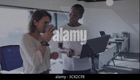 Zwei Kollegen in Geschäftskleidung diskutieren im modernen Büro über Laptop-Bildschirm mit blauem Kaffeetasse Stockfoto