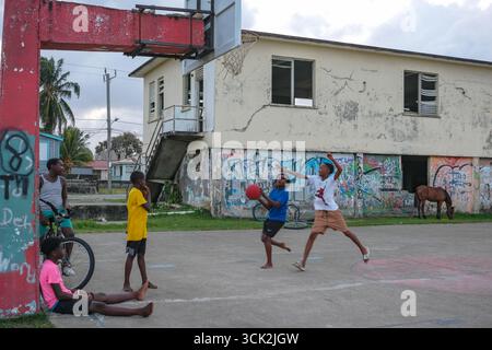 Dangriga, Belize - 6. Juni 2025: Jungs spielen Basketball auf der Straße in Dangriga, Belize. Stockfoto