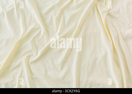 Nahaufnahme cremefarbene, faltige Textur, zerknitterter weißer Stoffhintergrund. Stockfoto