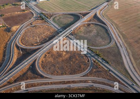 Blick aus der Vogelperspektive auf die wunderschöne Autobahnkreuzung in Kleeform an Sommertagen. Logistikkonzept Stockfoto