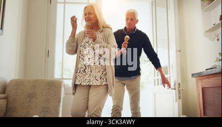 Seniorenpaar, Tür und Haus mit Eis zum Nachtisch, Date oder Bindung zusammen im Ruhestand. Ältere Menschen, Mann und Frau gehen mit Imbiss oder Kegel hinein Stockfoto