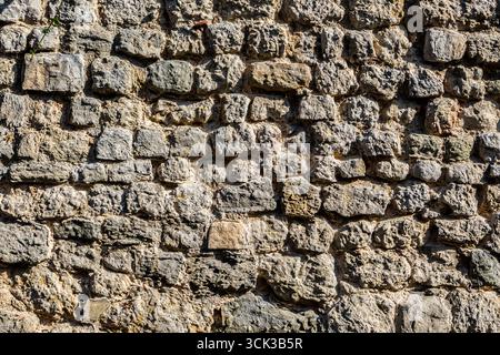 Eine Detailaufnahme einer alten rauen Steinmauer in Hythe, Kent, Großbritannien Stockfoto