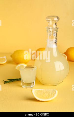 Schuss und Flasche leckeres Limoncello auf beigefarbenem Hintergrund Stockfoto