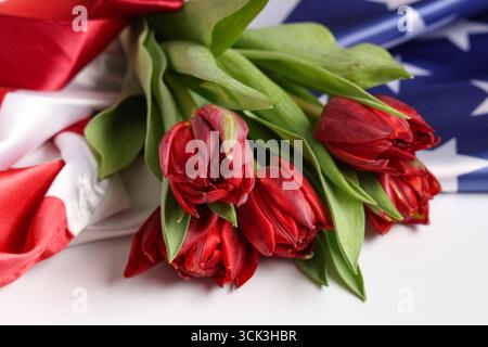 Wunderschöne Tulpenblumen und Flagge der USA auf hellem Hintergrund, Nahaufnahme. Gedenkfeier Stockfoto
