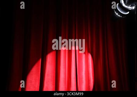 Strahlender Spotlight auf rotem Vorhang Stockfoto