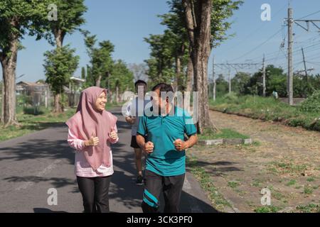 Eine Gruppe von Freunden, die gemeinsam joggen, während sie einen wunderschönen Outdoor-Pfad durchqueren Stockfoto