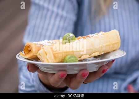 Teller mit köstlichen Waffelbrötchen mit Stachelbeeren. Waffelbrötchen mit Beeren und Puderzucker. Waffle Tobes oder Rolls. Hausgemachtes Dessert. Stockfoto