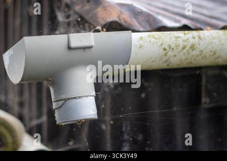 Nahaufnahme der Regenrinne aus Kunststoff und des rostigen Zinndachs Stockfoto
