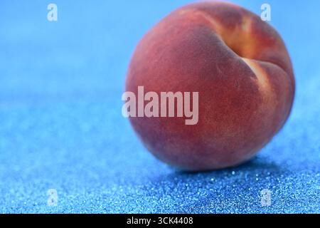 Frischer Pfirsich auf funkelndem blauem Hintergrund Stockfoto