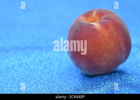 Frischer Pfirsich auf funkelndem blauem Hintergrund Stockfoto